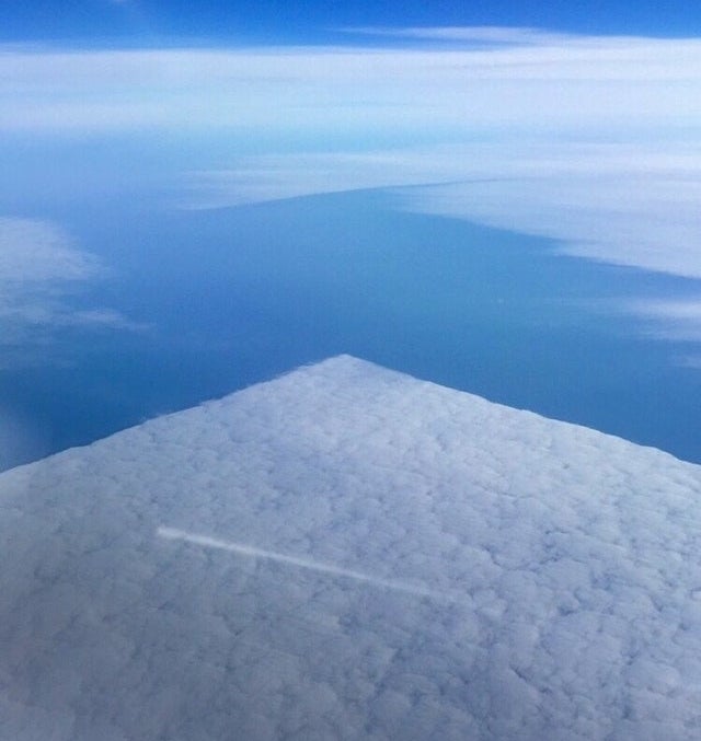 A perfectly square-shaped area of clouds seen from above, from a plane window