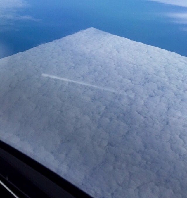 A perfectly square-shaped area of clouds seen from above, from a plane window