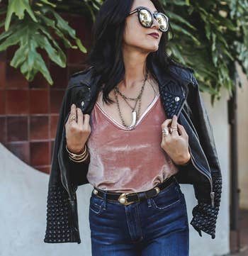 A reviewer wearing the cami in pink, styled with jeans and a leather jacket