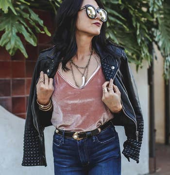 A reviewer wearing the cami in pink, styled with jeans and a leather jacket
