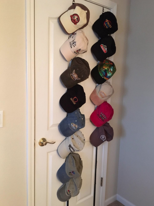 A customer review photo of the cap rack hanging on their door with all their hats. 