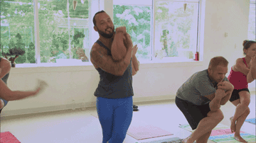 A man struggles to do a yoga pose in a class