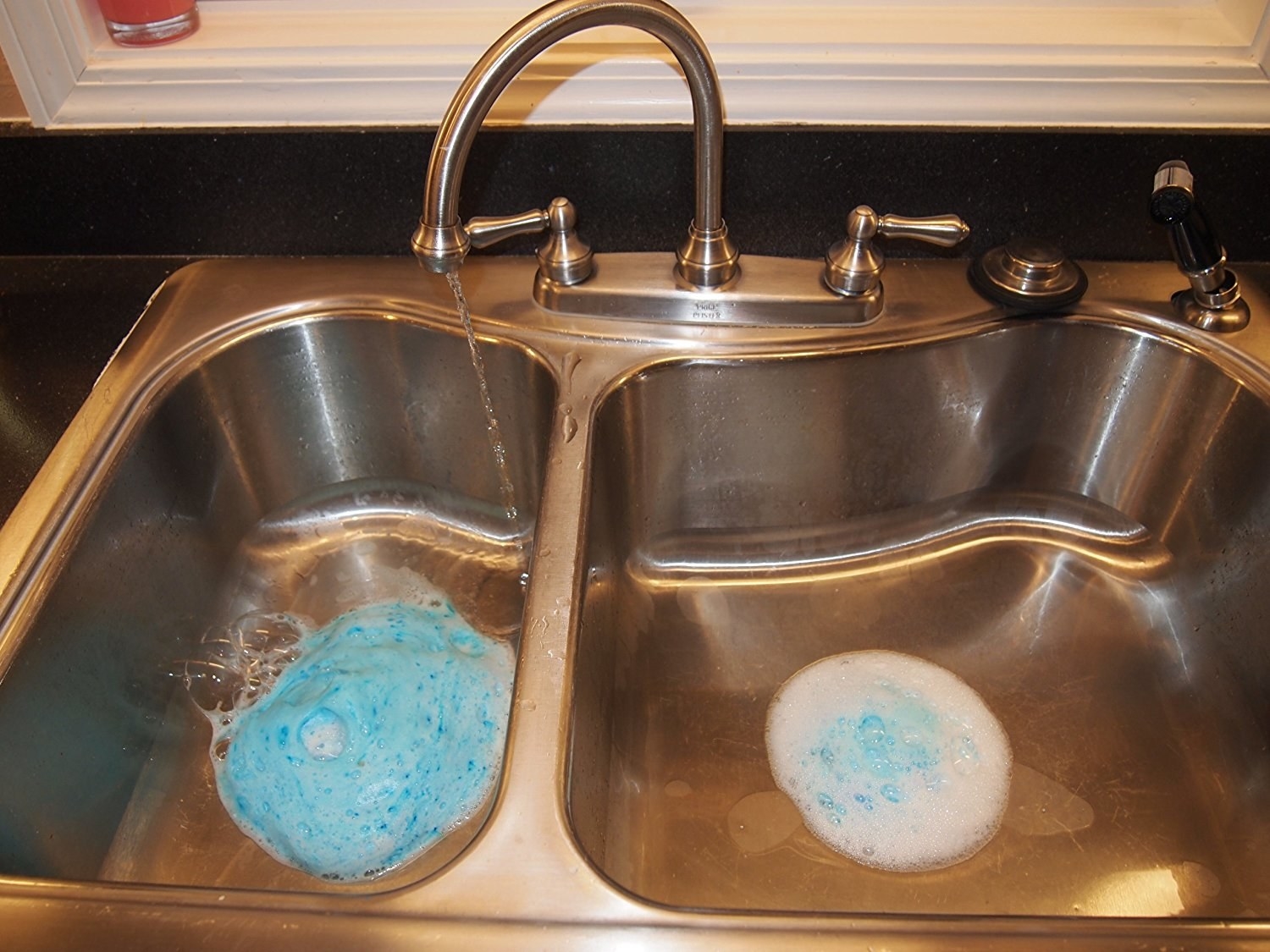double kitchen sink with blue foam cleaner coming up from the drain