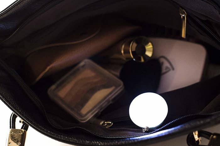 The bag light clipped to the inner pocket of a purse, lighting up the interior of the bag