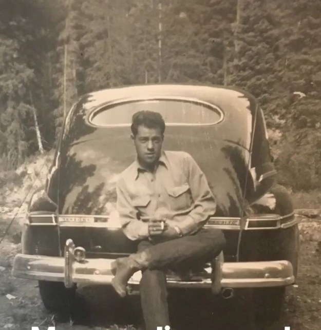 A man in an old photograph from years ago, sitting on a car