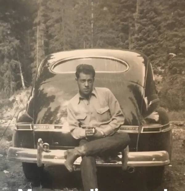 A man in an old photograph from years ago, sitting on a car