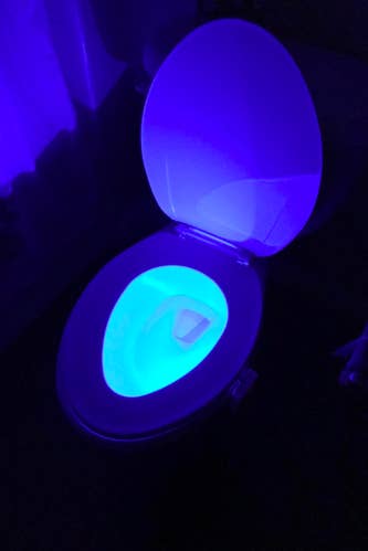 A reviewer photo of a toilet in the dark with the bowl lit up in blue