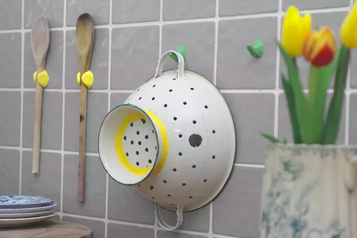 colander and wooden spoon held onto a tile kitchen wall with hooks and holders made from the moldable glue