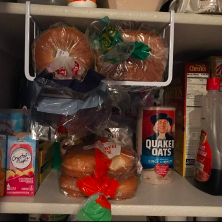 reviewer pic of the slide on shelf basket that's hanging below a shelf and holding loaves of bread in otherwise unused space