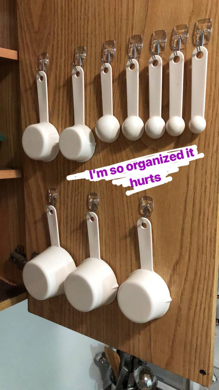 writer&#x27;s pic of inside of a kitchen cabinet with mounted Command hooks to hanging measuring cups and spoons from 