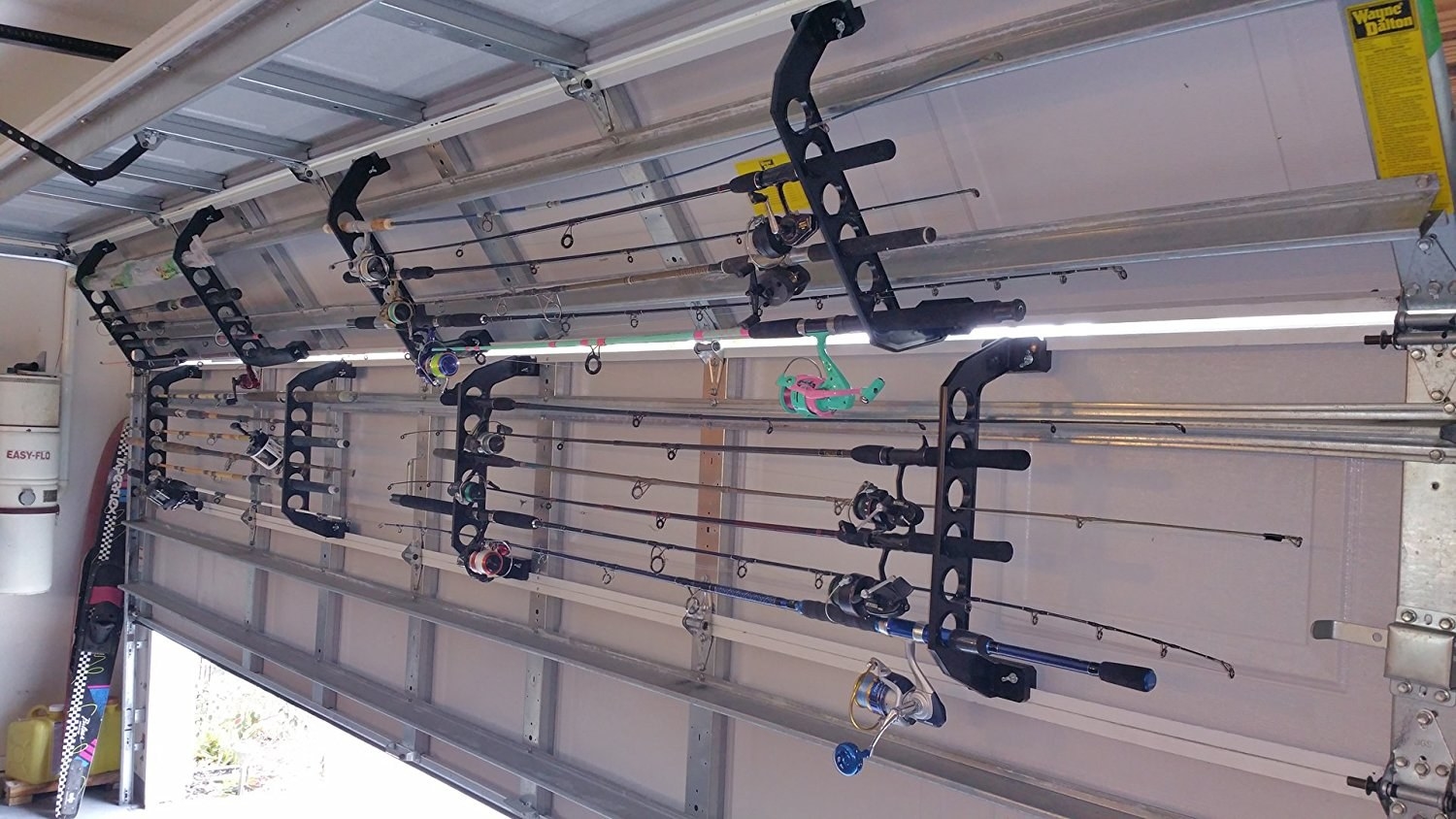 inside view of a garage with raising garage doors with the racks with fishing rods stored horizontally on the doors