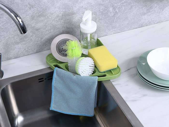 kitchen sink with green triangle shaped sponge and soap holder on the corner of a sink