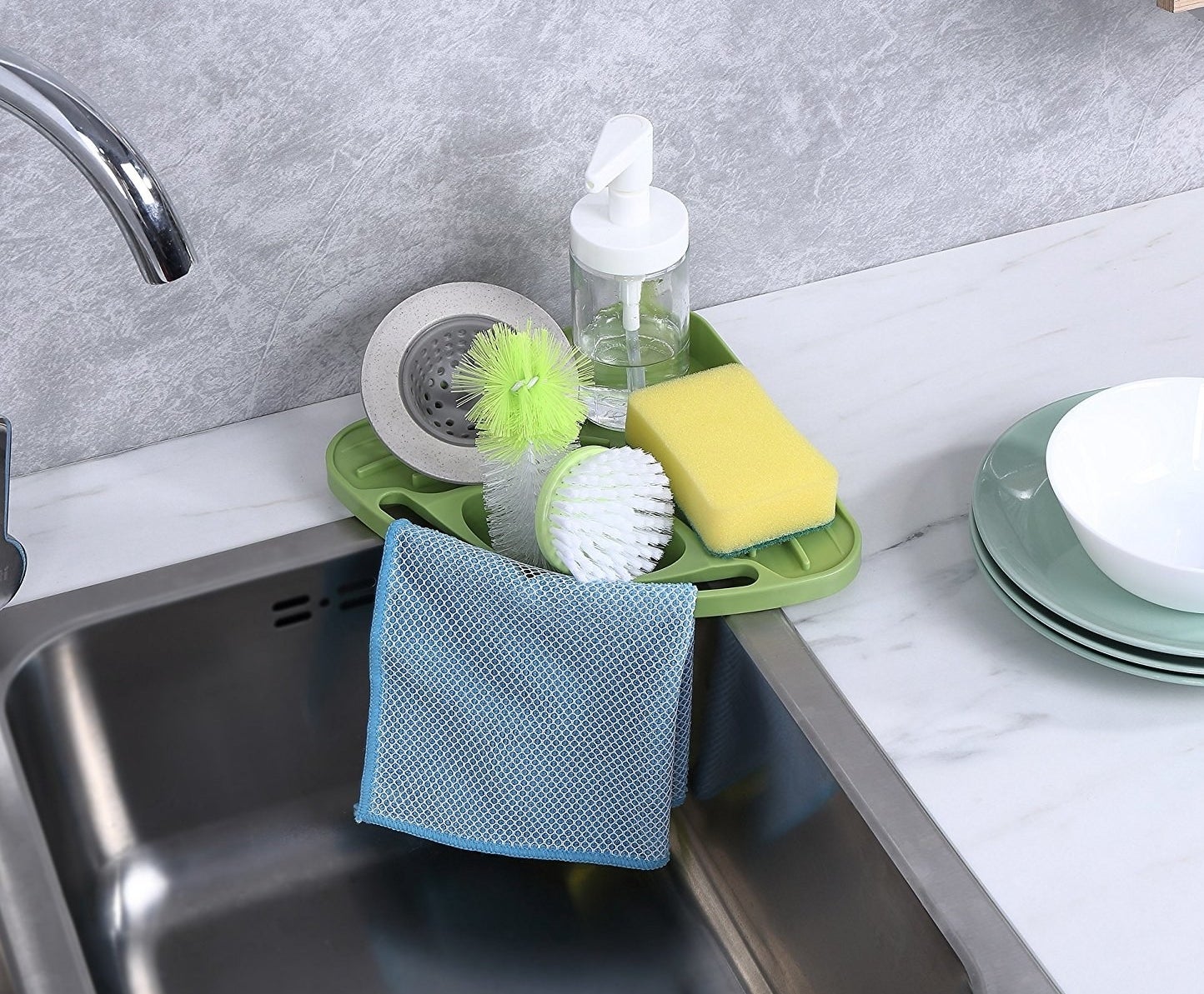 kitchen sink with green triangle shaped sponge and soap holder on the corner of a sink