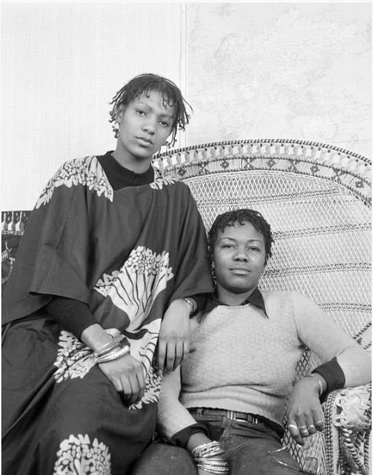 Anti-discrimination, women's and squatters' rights activist, Olive Morris (right) with friend Lia Obi posing in a Huey Newton style chair, used by the American Black Panthers. Olive's community work was recognised by Lambeth Council in 1986 when they named an office building Olive Morris House.