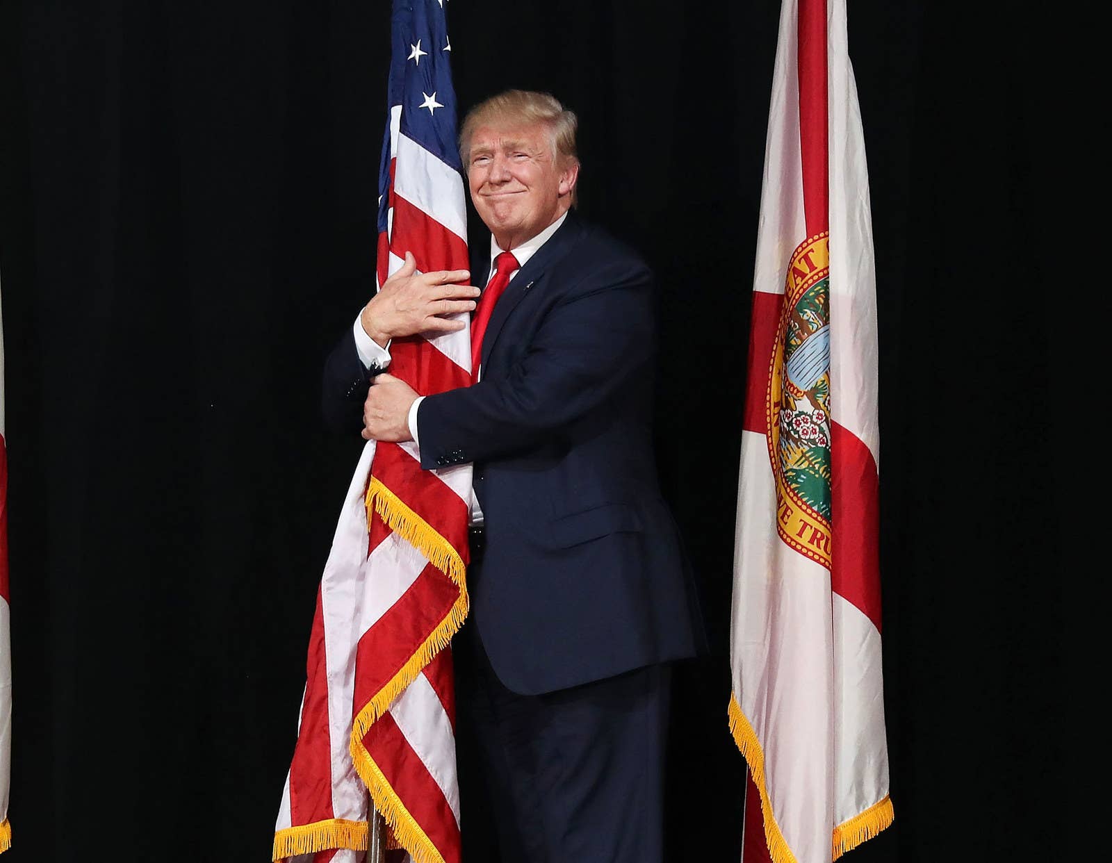 Republican presidential candidate Donald Trump hugs the American flag as he arrives for a campaign rally on Oct. 24, 2016, in Tampa, Florida.