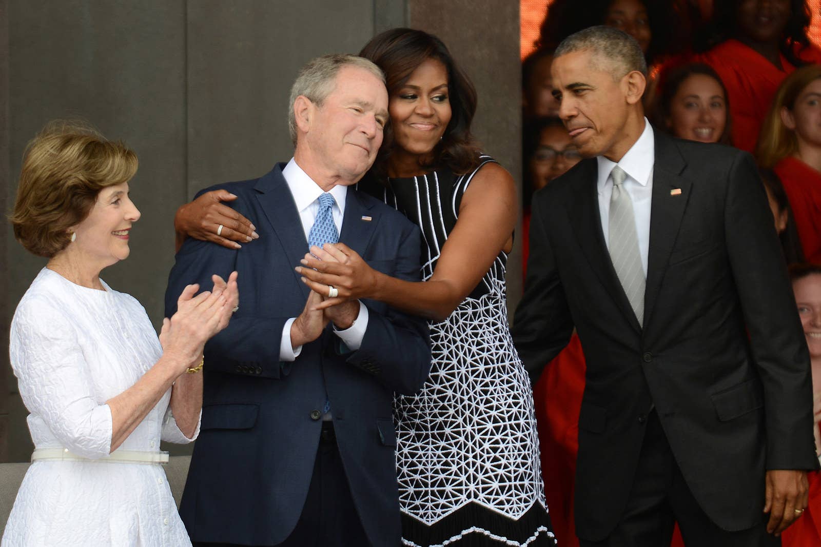 President Barack Obama watches first lady Michelle Obama embrace former president George Bush, accompanied by his wife, former first lady Laura Bush, while participating in the dedication of the National Museum of African American History and Culture on Sept. 24, 2016, in Washington, DC.