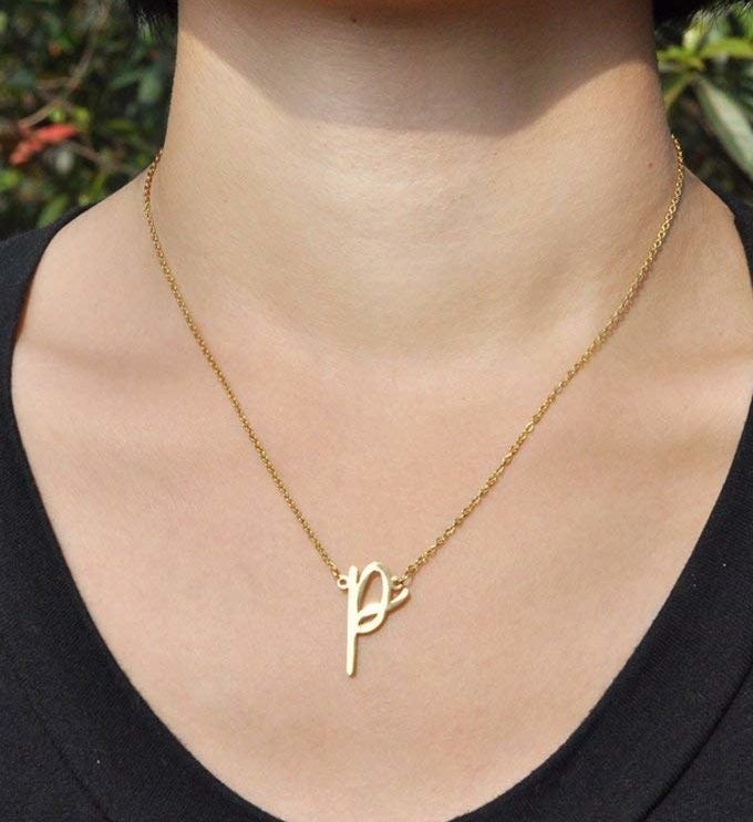 A model wearing the gold necklace with a letter &quot;P&quot; pendant