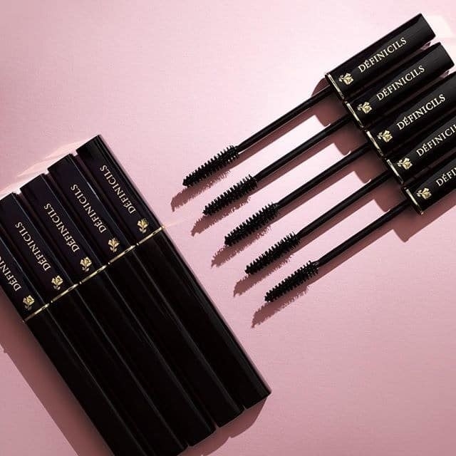 five mascara tubes with the top on and five mascara wands open