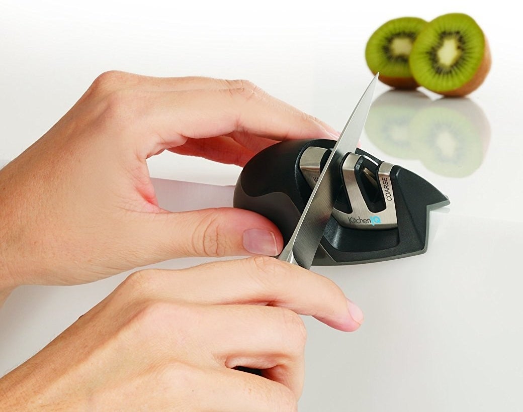 A hand sharpening a knife with the sharpener