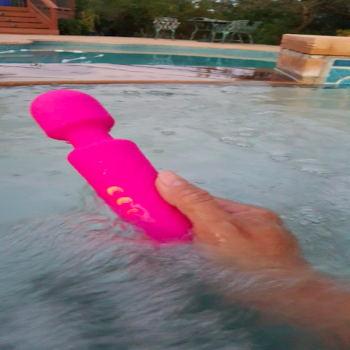 a reviewer holding the pink wand in a hot tub