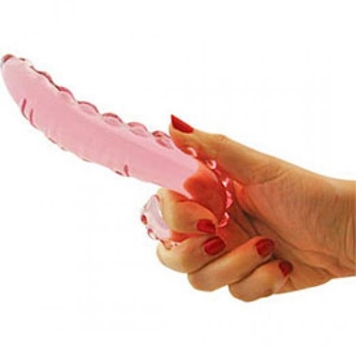 a hand holding the textured pink glass dildo