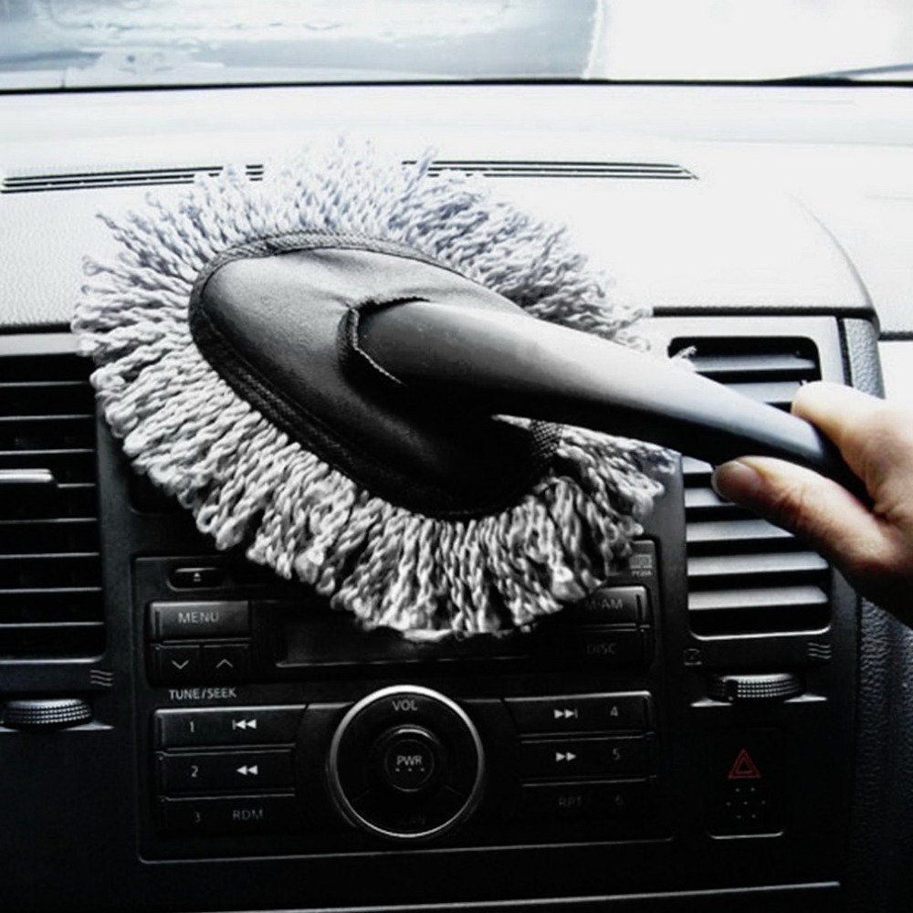 A person using the car duster to clean their car radio