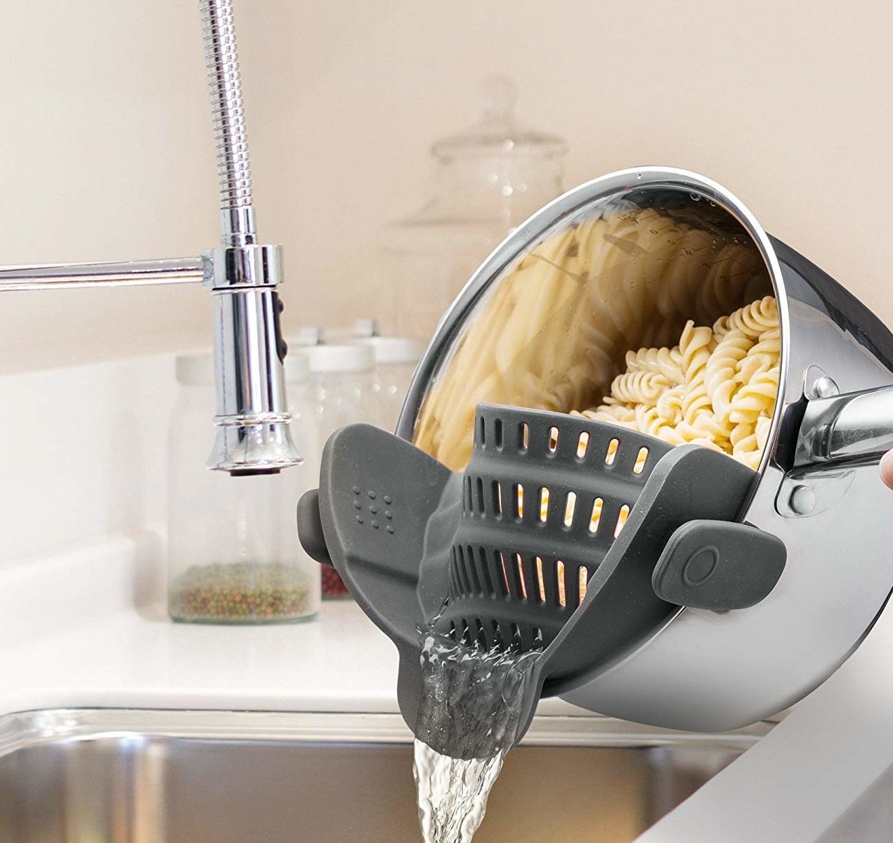 The strainer attached to a pot, which allows the water to drain while keeping pasta in place