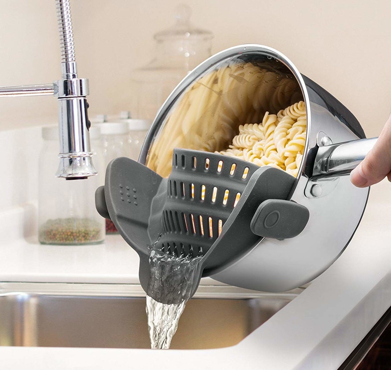 The strainer attached to a pot, which allows the water to drain while keeping pasta in place