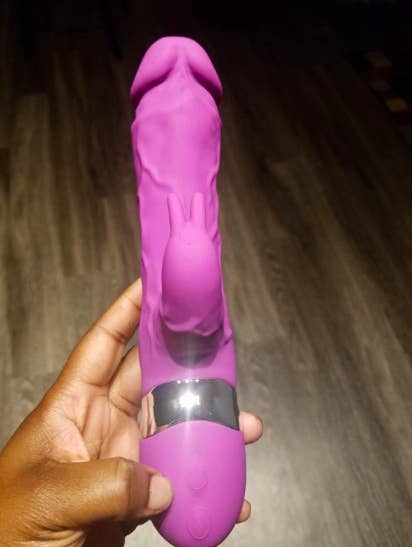 A reviewer holding the large dildo, showing the raised veins and the rabbit ear clitoral stimulator 