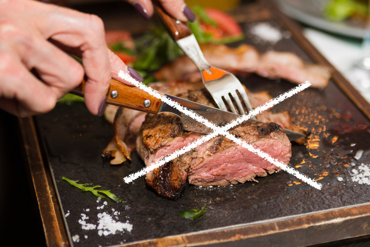 Person cutting a freshly cooked piece of steak. The picture has a white &quot;X&quot; going through it, indicating that this is not a good practice