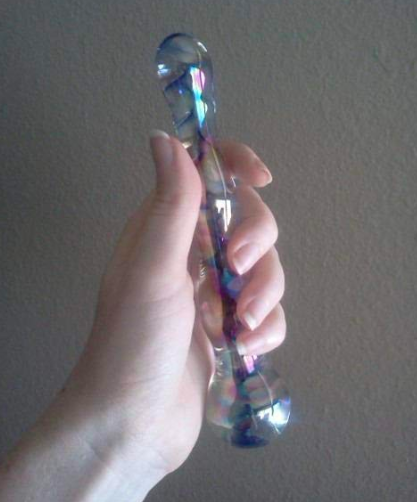 A reviewer holding the colorful glass dildo, showing the smooth bubbles formed around the sides 