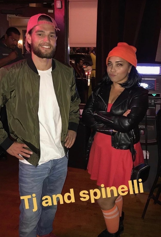 A man in a backwards baseball cap and bomber jacket next to a woman with a leather jacket, hair in pigtails, and a beanie. 