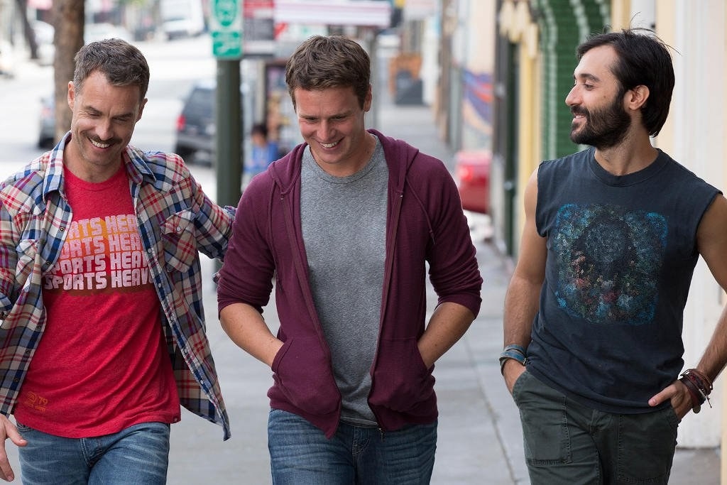 Characters Dom, Patrick Murray, and Agustin smile as they walk down the street together