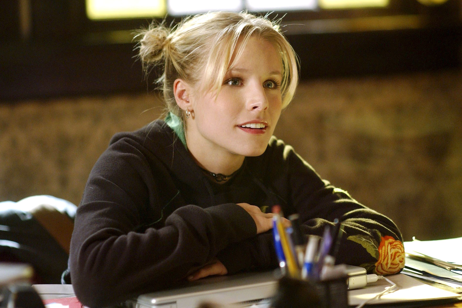 Kristen Bell as Veronica with her arms leaning on a desk