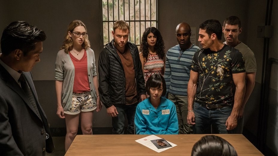 Characters from Sense8 standing around Bae Doona as Sun, who is seated
