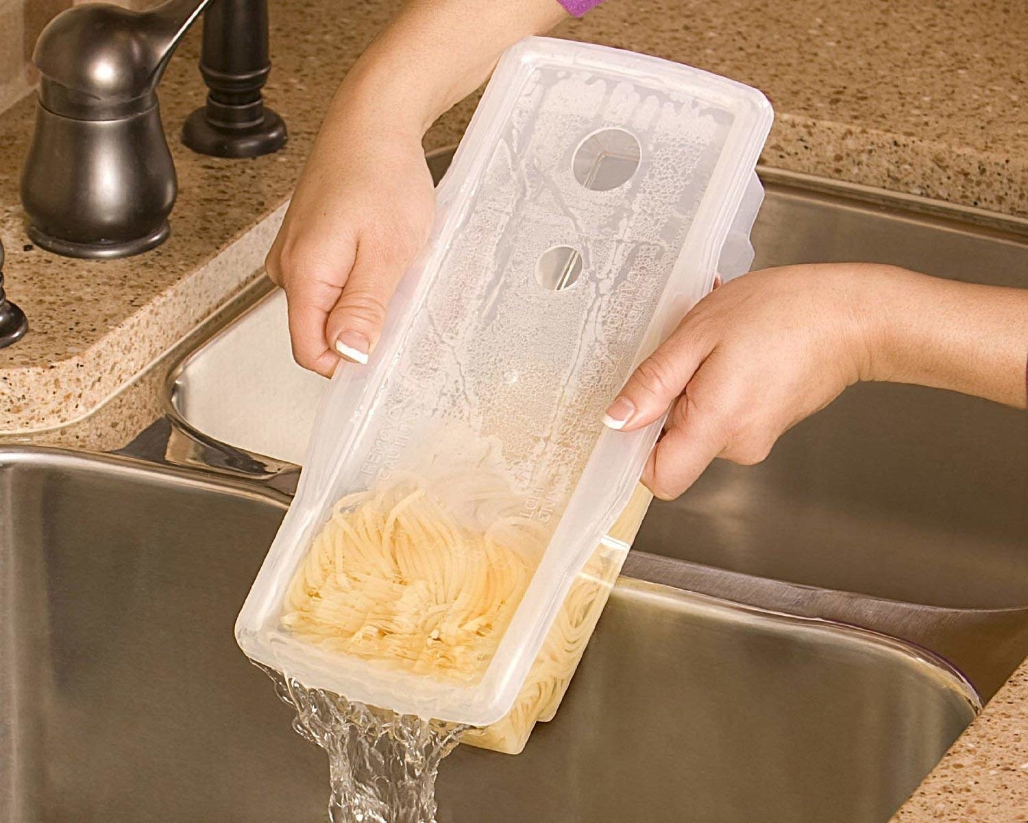 A model holds the Fasta Pasta, a rectangular container with cooked pasta inside, over a sink as they strain the water out