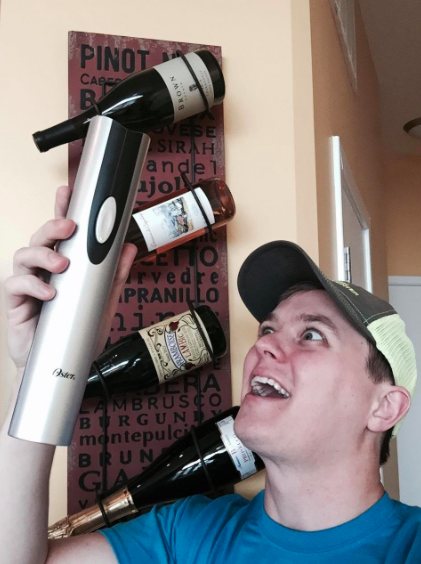 reviewer lovingly holds up electric opener that is silver and cylindrical in shape. 