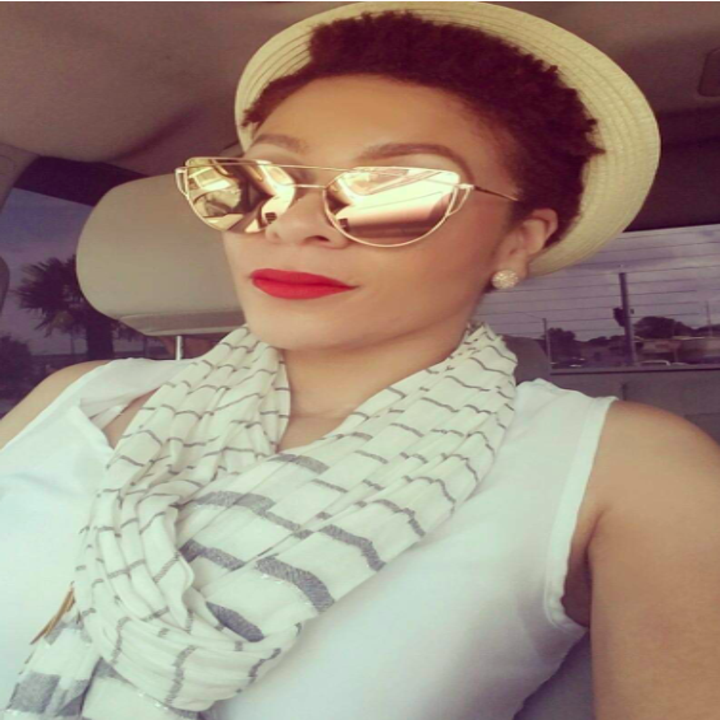 A reviewer wearing the cat-eye sunglasses with a wire bar detail across the top in gold