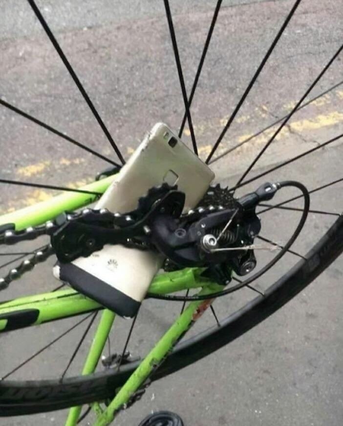 A person&#x27;s phone is broken in the spokes of a bicycle