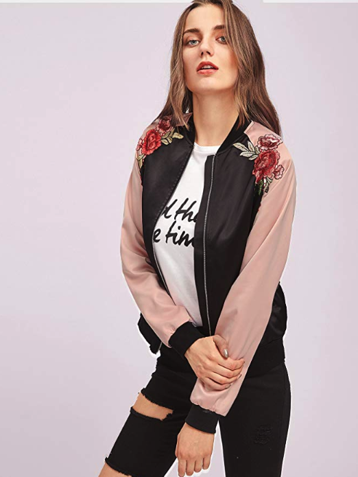Model wearing the black bomber jacket with light pink sleeves and embroidered red flowers on the shoulders. 