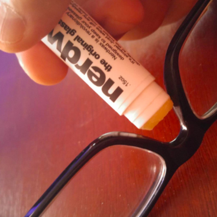 A reviewer applying the nerdwax to their glasses
