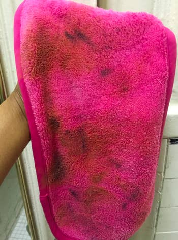 reviewer's hot pink cloth with black and brown makeup stains all over it
