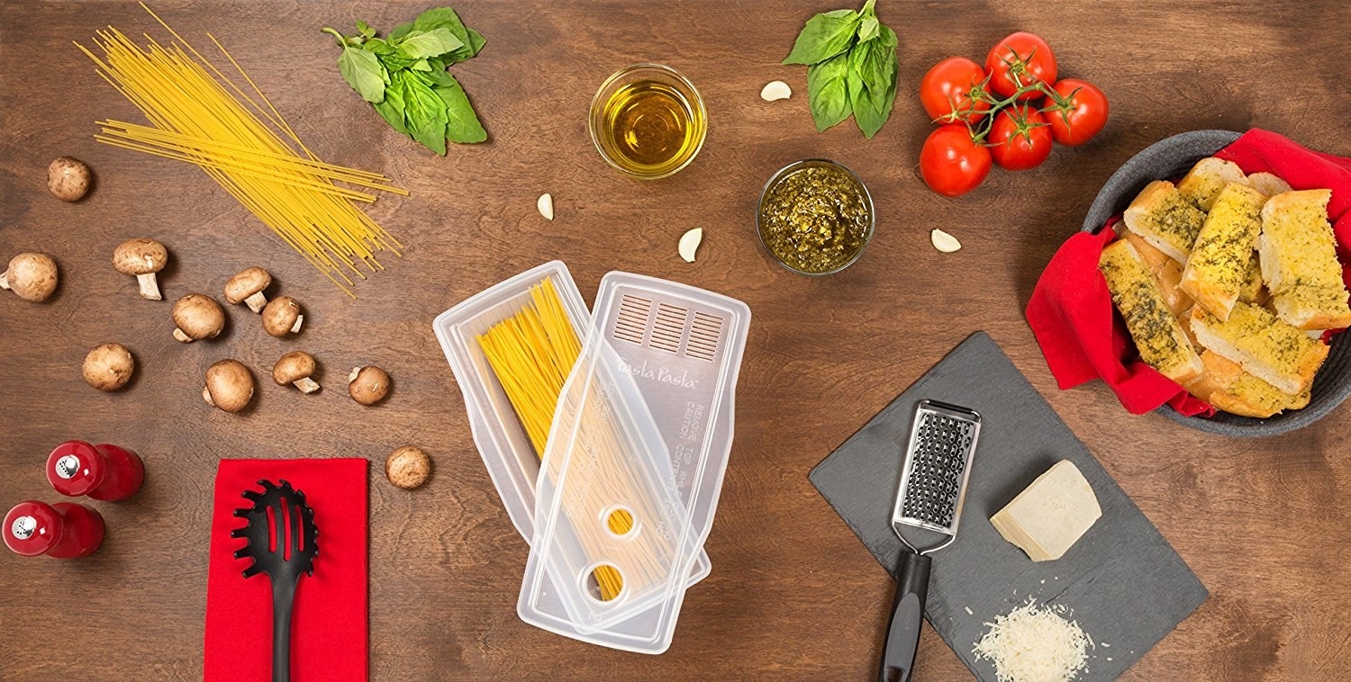 The rectangular cooker with spaghetti inside, plus the lid with strainer and two measuring holes for pasta