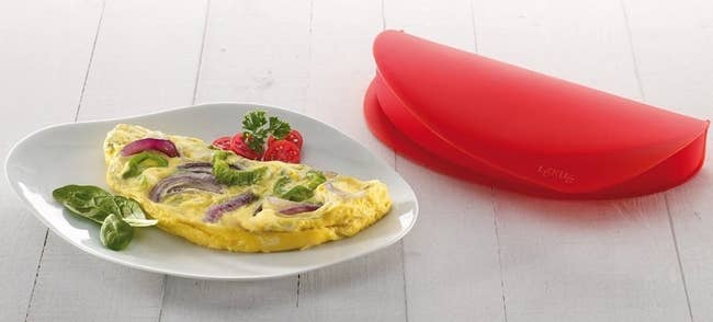 An omelet on a plate next to the red silicone mold
