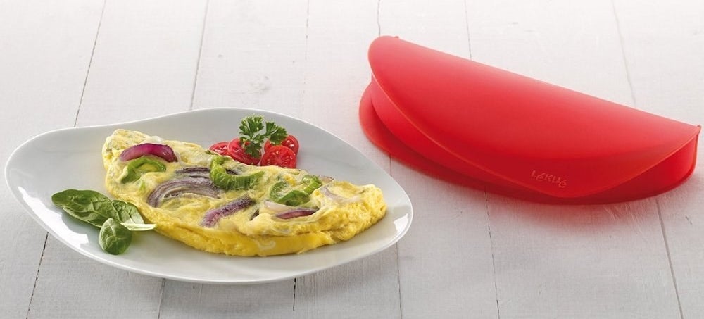 An omelet on a plate next to the red silicone mold