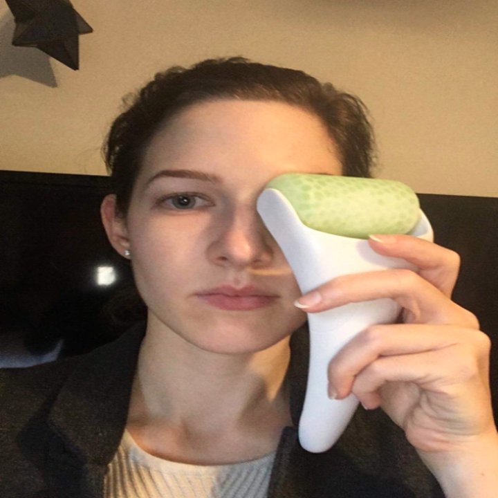 reviewer holding the plastic-handled roller over their eye