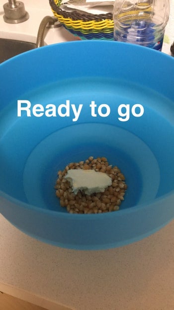 kernels in the bottom of the blue silicone bowl with butter and the text 