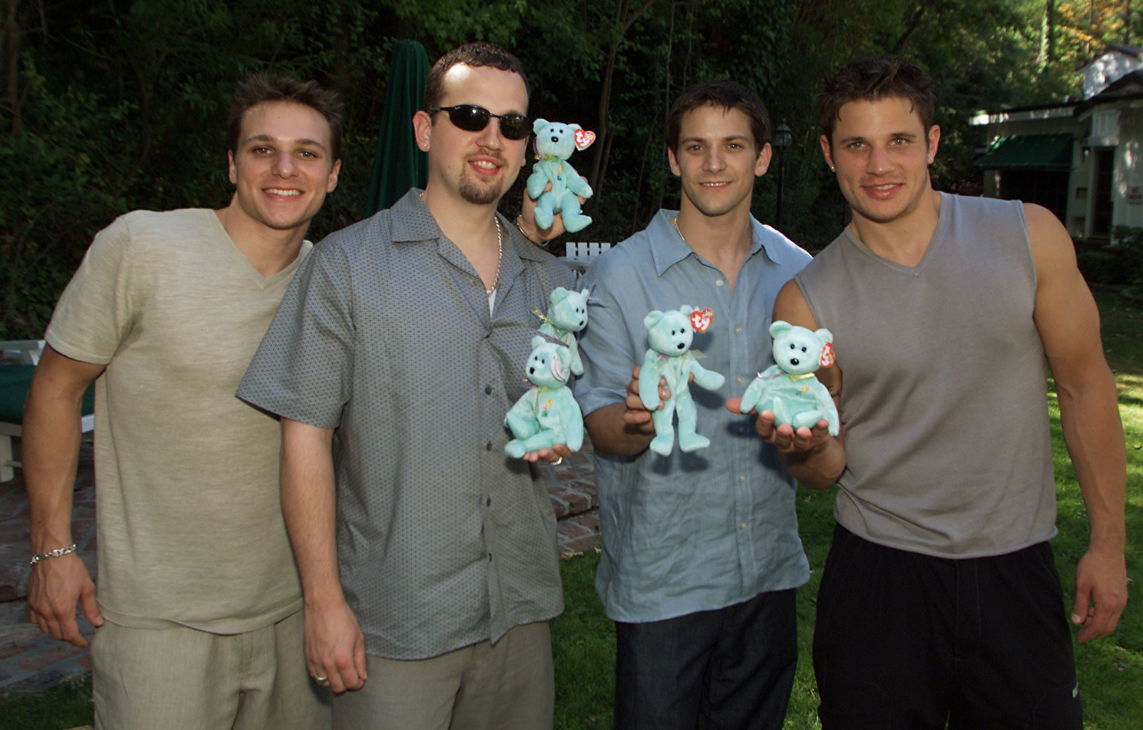 Nick Lachey, Jeff Timmons, Drew Lachey, and Justin Jeffre outside and holding blue Beanie Babies