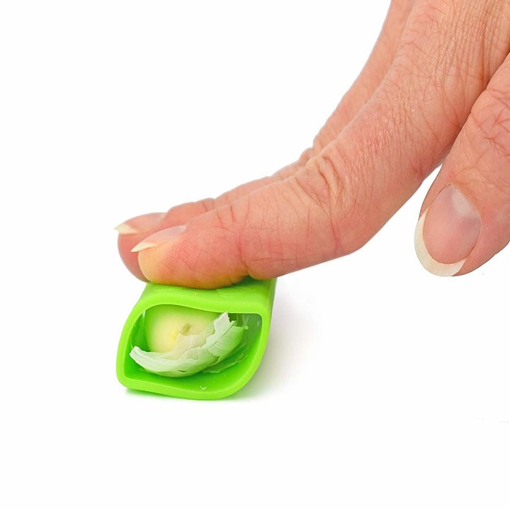 a hand using the garlic peeler