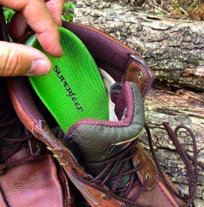 A review image of an insole being taken out of a worn hiking boot, the insole is new and already clearly formed to the owner's foot